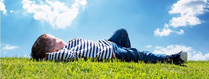 Child in the grass enjoying the sun and the sky